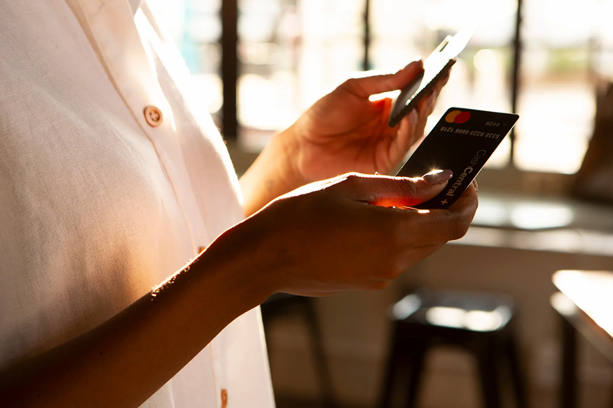 Person using a smartphone while holding a CashCentral reloadable cash card.